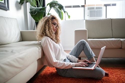 woman sitting on floor typing on laptop